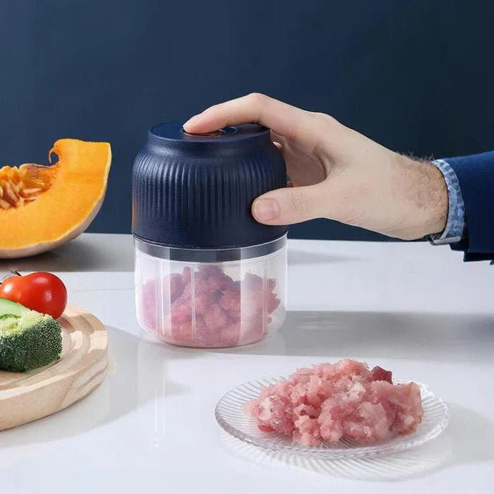 Electric Garlic Chopper in use, chopping meat and vegetables on a kitchen table.